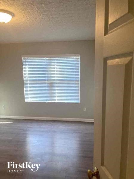 A room with a window covered in blinds and a door on the right.