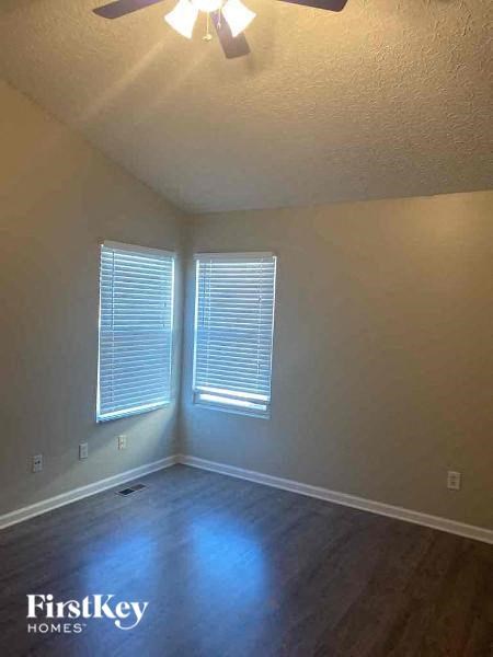 A room with a ceiling fan and two windows.