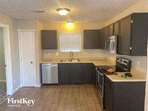 A kitchen with black cabinets and a stainless steel dishwasher.