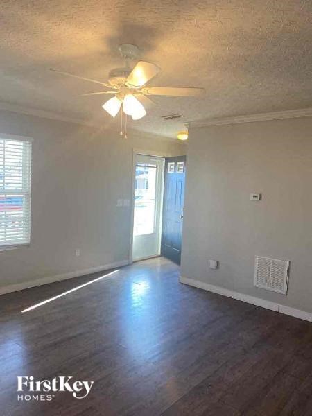A room with a ceiling fan and wooden flooring.