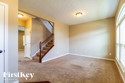 A room with a carpeted floor and a staircase leading to the upper level.