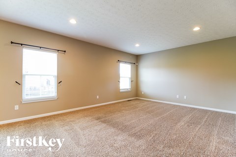 A room with a carpeted floor and two windows.