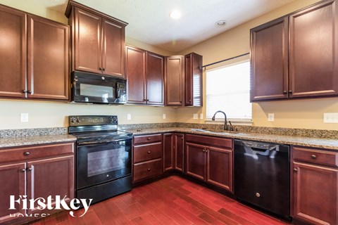 A kitchen with brown cabinets and a black dishwasher.
