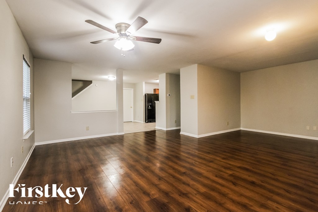 A spacious room with wooden floors and a ceiling fan.