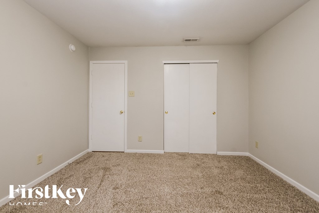 A bedroom with two closets and a carpeted floor.