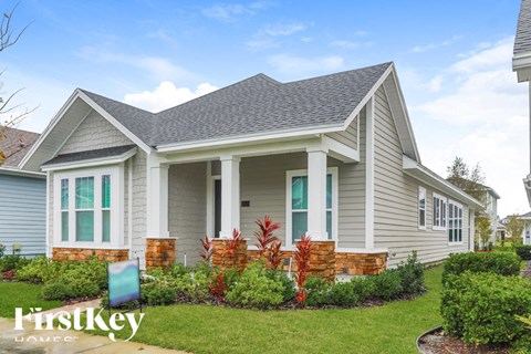 A house with a grey siding and a brick pillar in front.