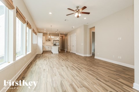A spacious room with wooden flooring and a ceiling fan.