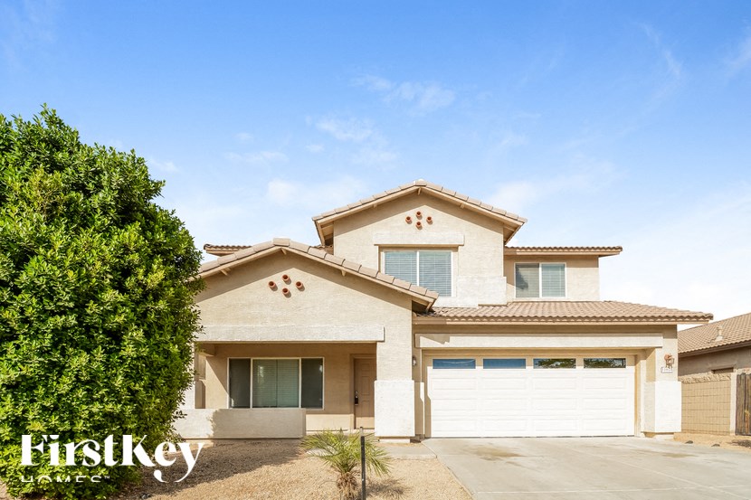 A house with a garage and a tree in front of it.