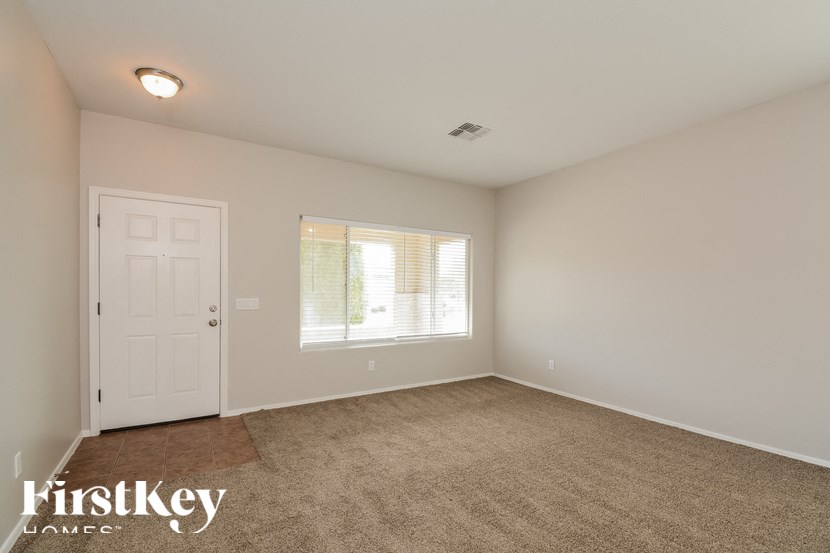 A room with a carpeted floor, a door, and a window with blinds.