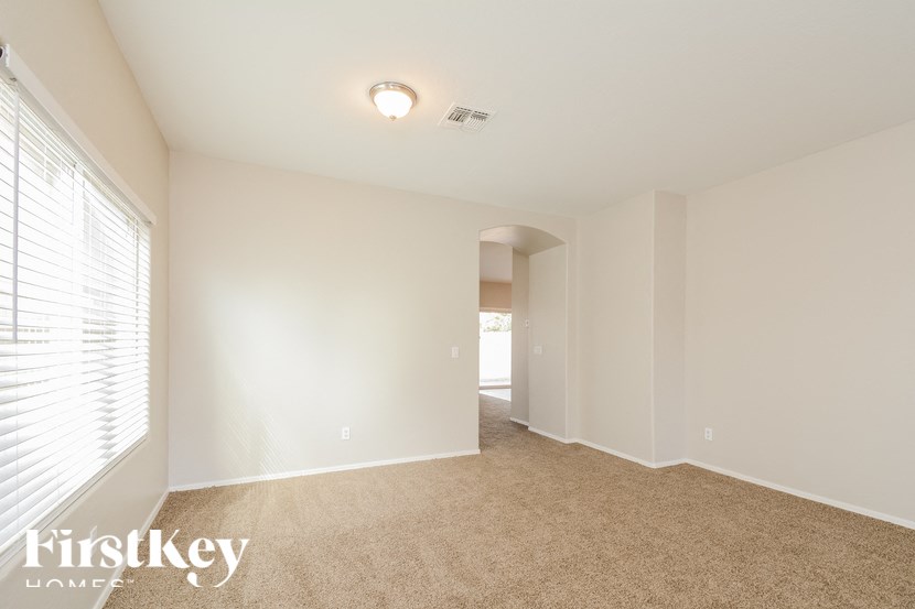 A spacious room with a carpeted floor and a window with blinds.