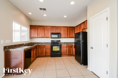 A kitchen with brown cabinets and black appliances.