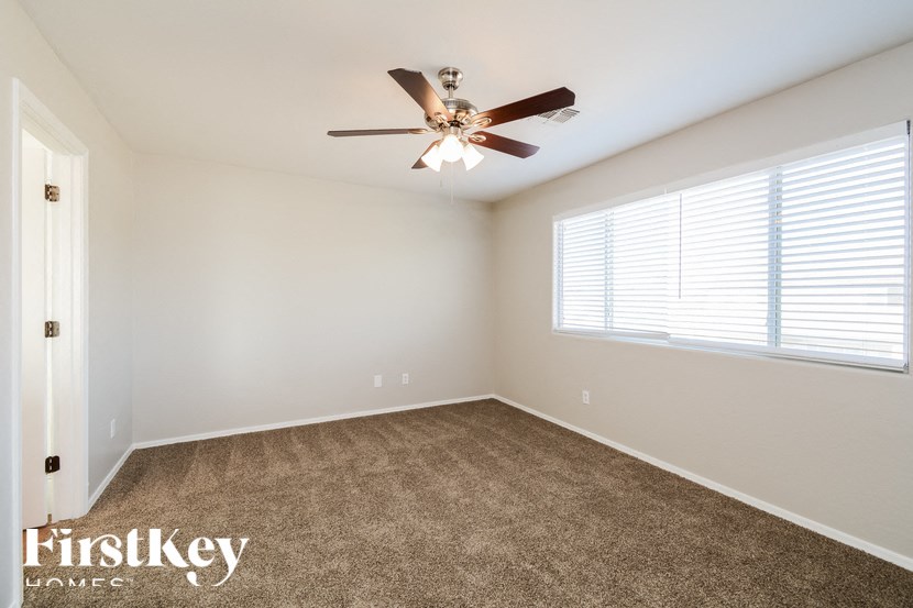 A room with a ceiling fan and carpeted floor.