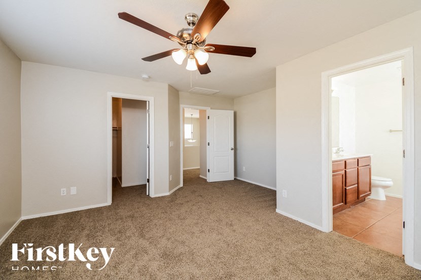 A spacious room with a ceiling fan and beige carpeting.