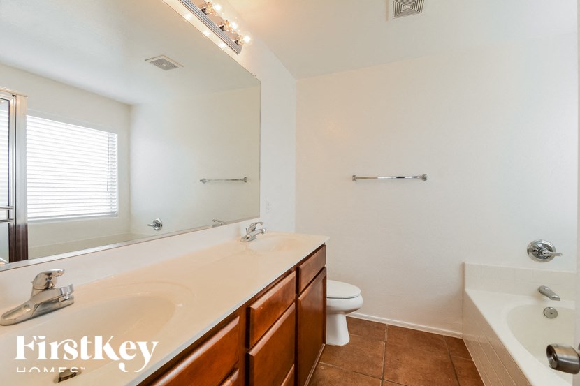 A bathroom with a white tub and a wooden vanity.