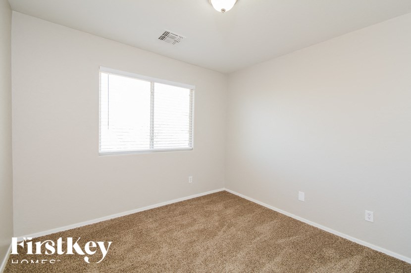 A room with a carpeted floor and a window with blinds.
