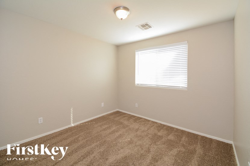 A room with a carpeted floor and a window with blinds.