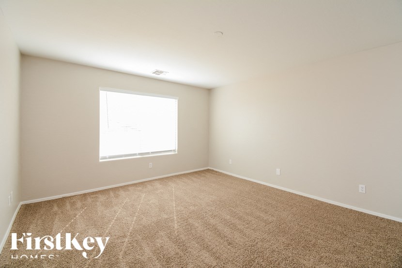 A room with a carpeted floor and a window letting in light.