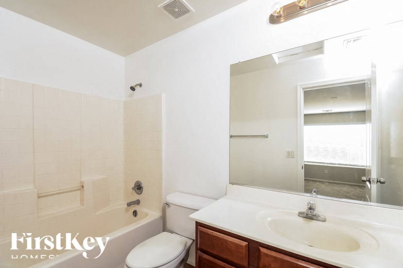 A white bathroom with a toilet, sink and mirror.