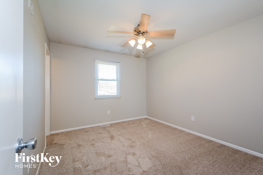 a bedroom with carpet and a ceiling fan and a window