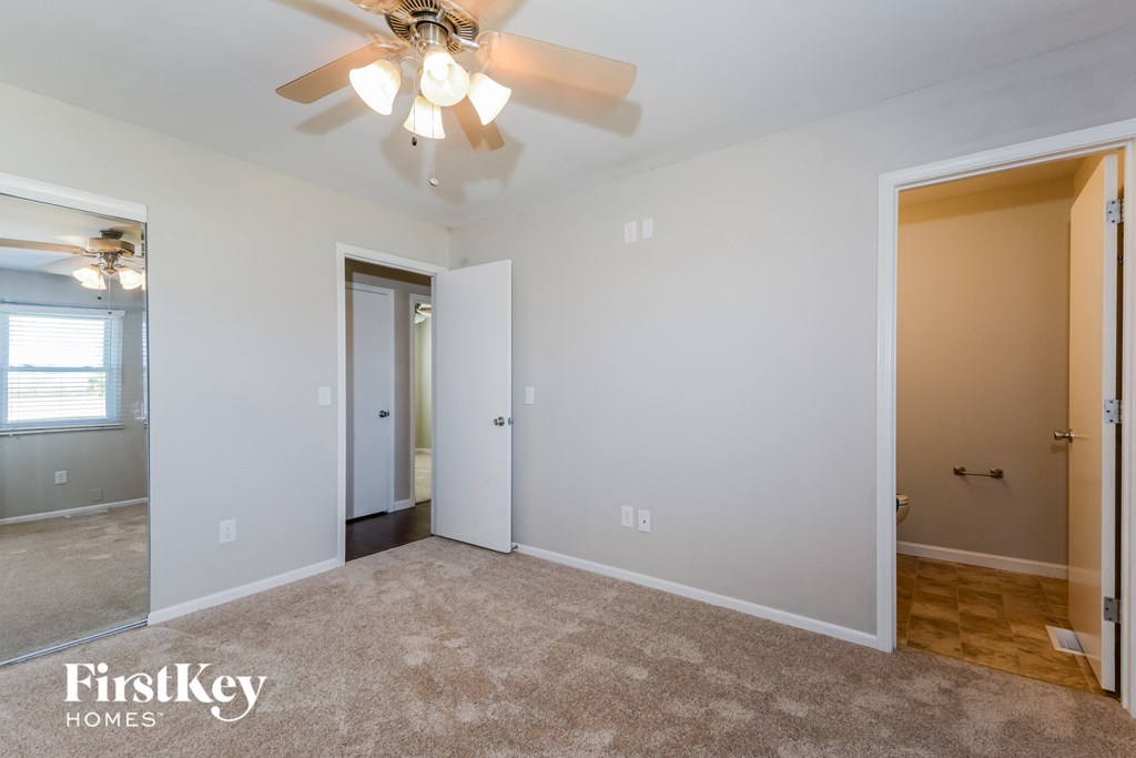 a living room with a ceiling fan and a door to a hallway
