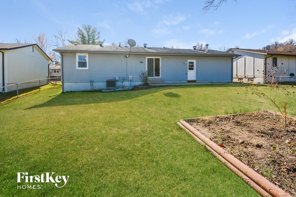a backyard with a blue house and a lawn