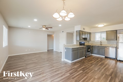 A well-lit kitchen with wooden floors and a ceiling fan.