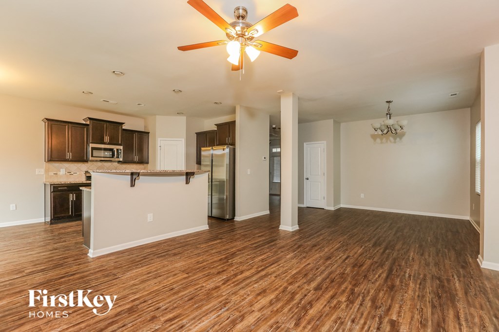 an open living room with a kitchen and a ceiling fan