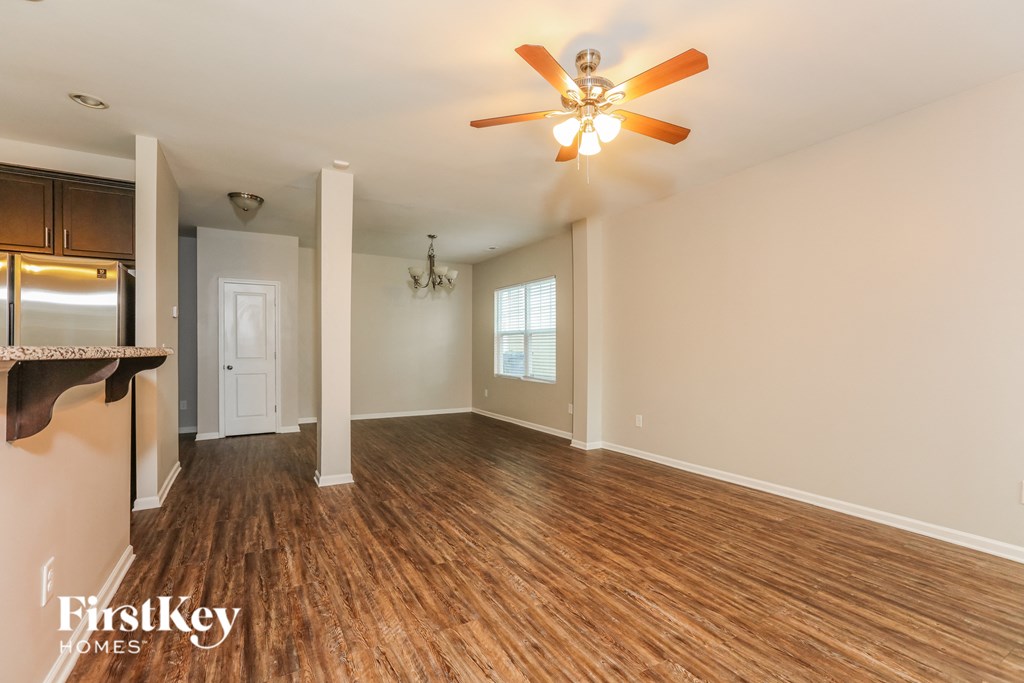 the living room and kitchen of an empty house with a ceiling fan
