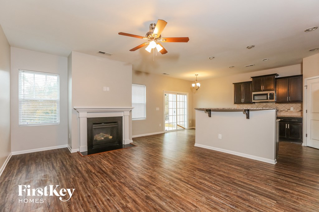 an empty living room with a fireplace and a ceiling fan