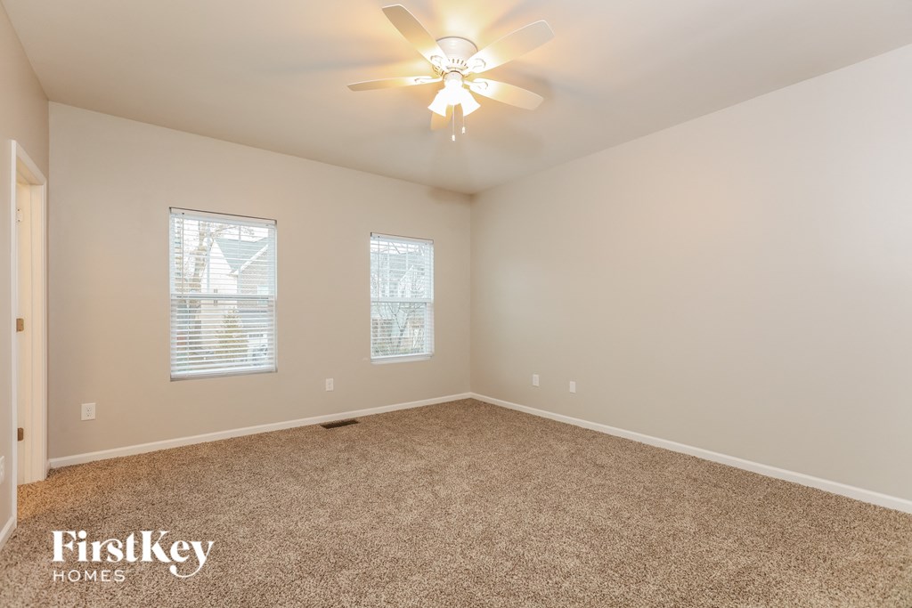 a bedroom with a carpeted floor and a ceiling fan