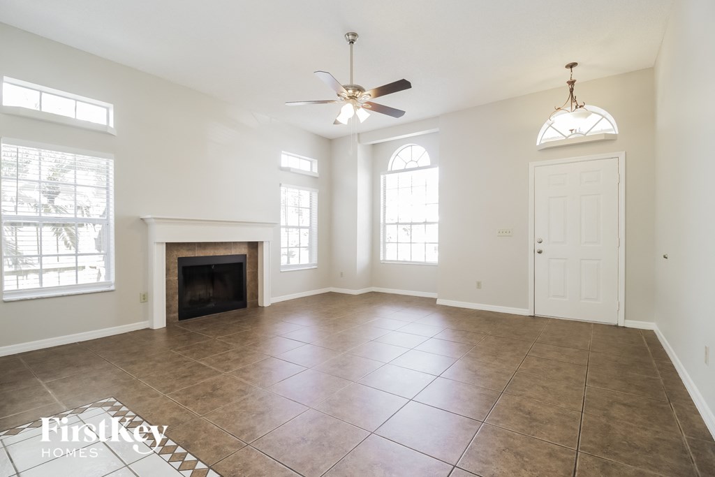 an empty living room with a fireplace and a ceiling fan