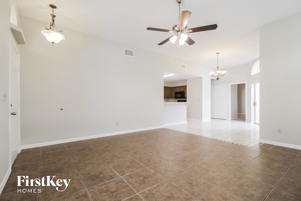 an empty living room with a ceiling fan and tile floor