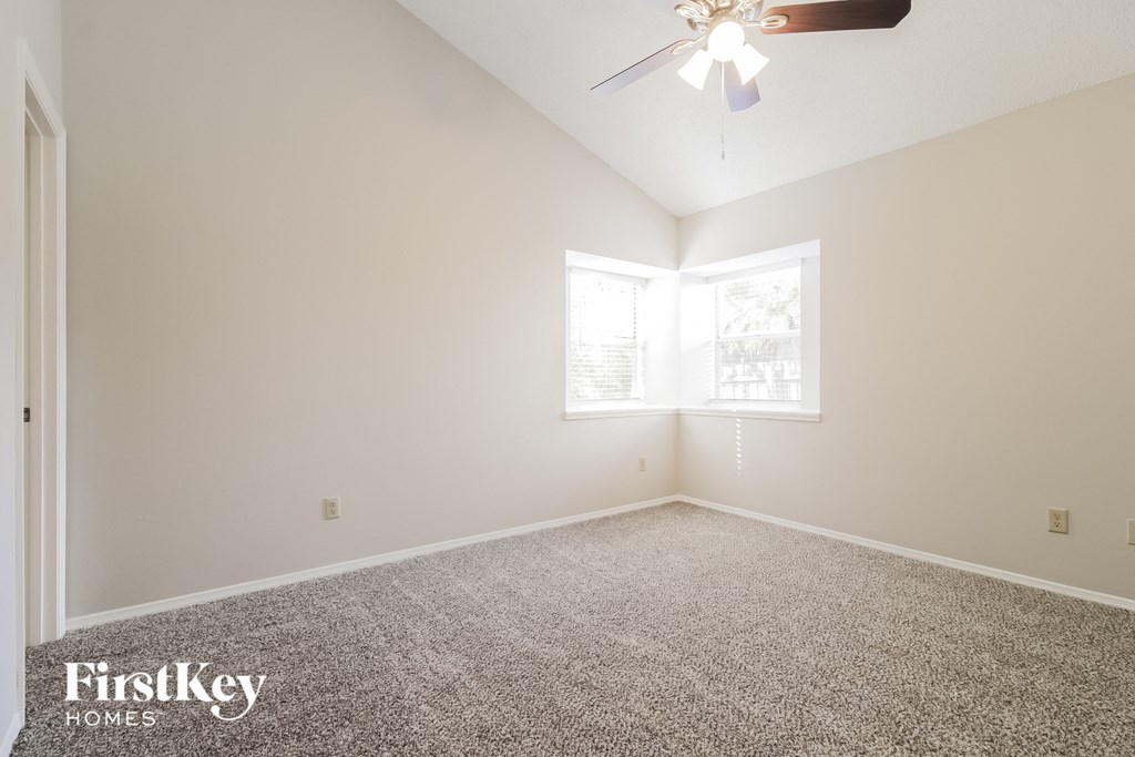 the spacious living room with carpeting and a ceiling fan