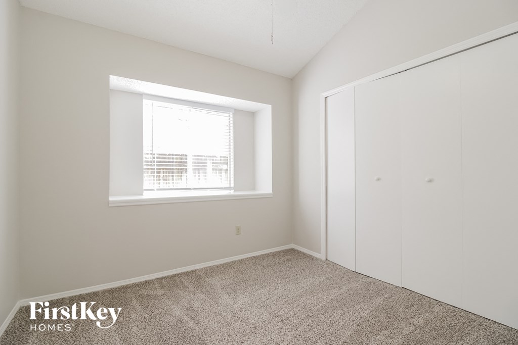 a bedroom with white walls and a window and a closet