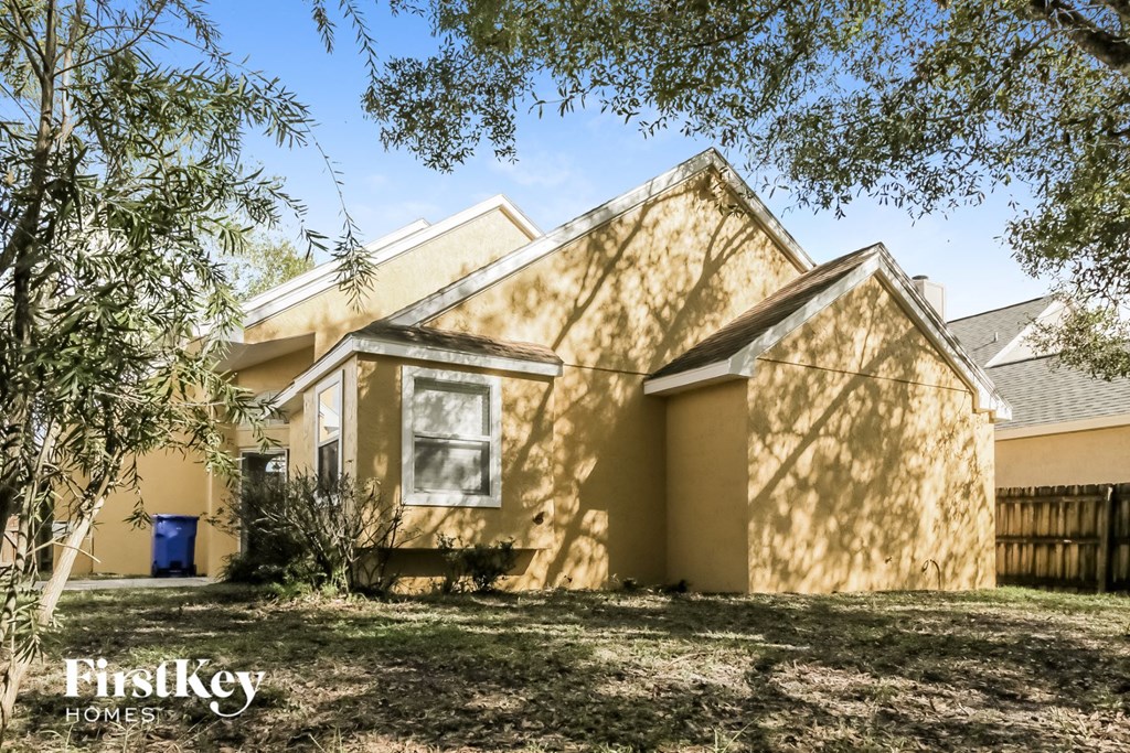 the front of a yellow house with a yard and trees