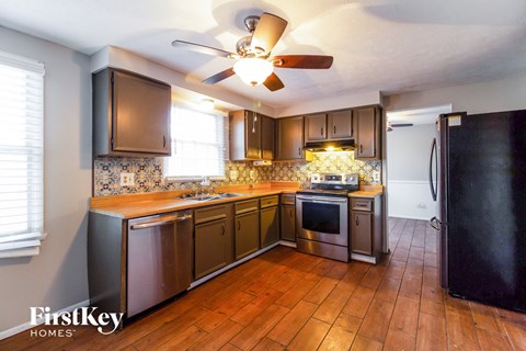 a kitchen with wooden counters and stainless steel appliances and a ceiling fan