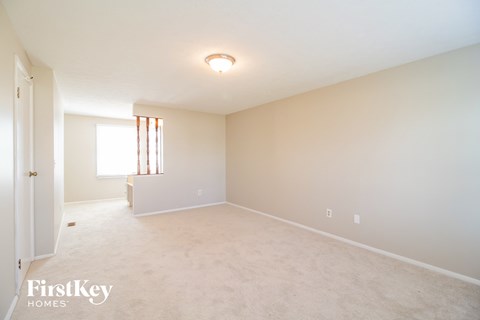 a spacious living room with white carpet and white walls and a window