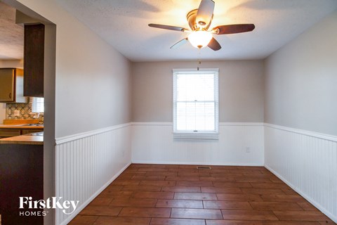 an empty dining room with a ceiling fan and a window