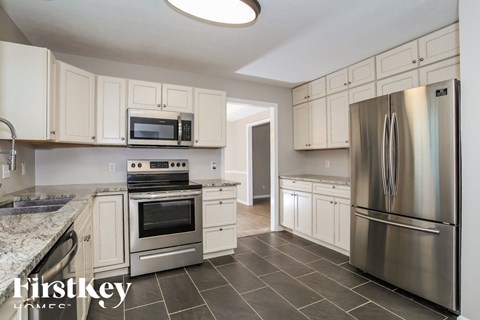 A kitchen with a refrigerator, oven, and microwave.