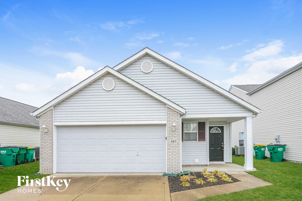 the front exterior of a white house with a green front yard