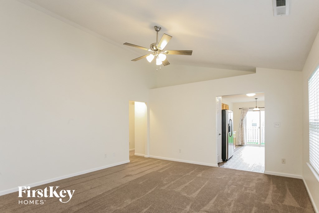 a living room with white walls and a ceiling fan