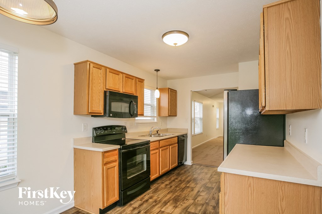 a kitchen with wooden cabinets and black appliances and a black refrigerator