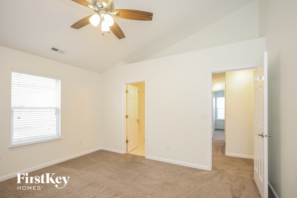 a bedroom with a ceiling fan and a door to a hallway