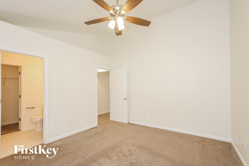 a living room with a ceiling fan and a door to a bathroom