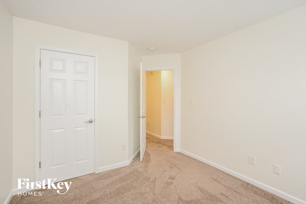 a bedroom with a white door and a carpeted floor