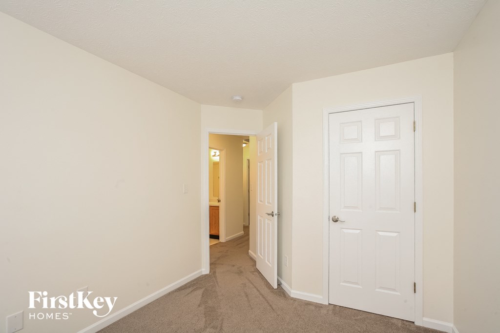 a bedroom with a white door and a hallway to a bathroom