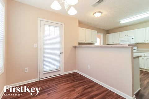 A kitchen area with wooden floors and white cabinets.
