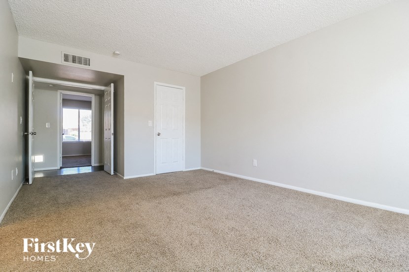 a spacious living room with carpet and a door to the bathroom