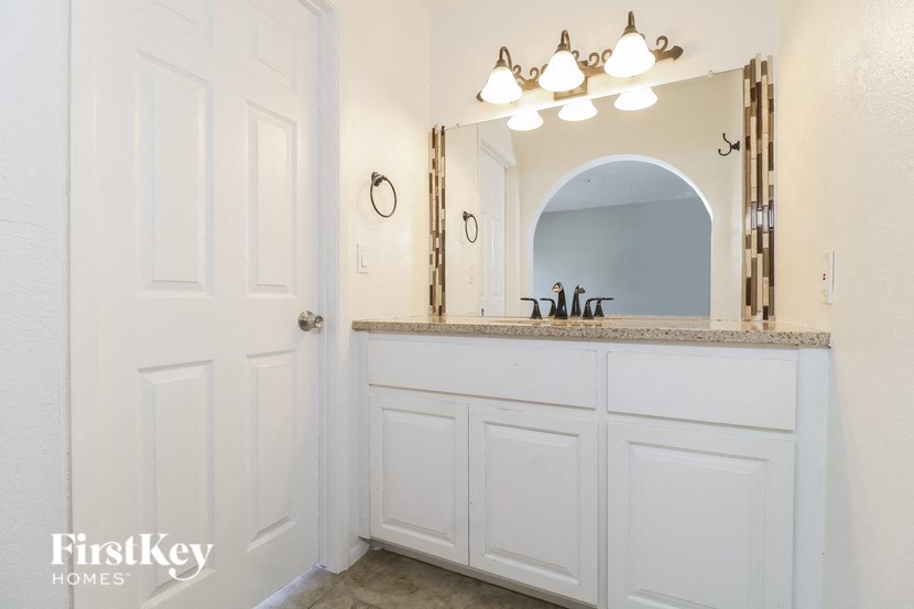 a bathroom with white cabinets and a sink and a mirror