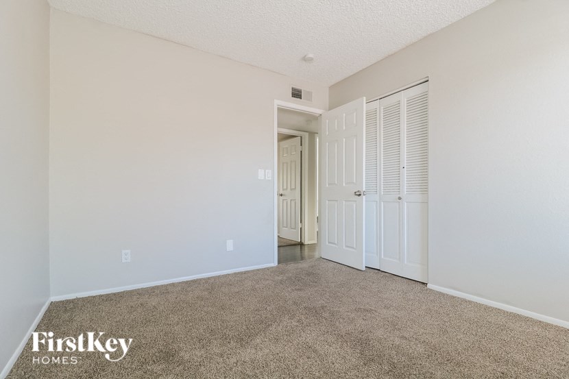 a spacious living room with carpet and a door to a hallway